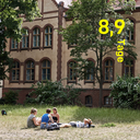 Vier Studierende liegen und sitzen auf einer großen Wiese auf dem Campus Nord. Es ist Sommer- Das Gras ist trocken. Die Sonne scheint. Der Text „8,9 Tage“ ist grafisch eingebunden. Foto: Julia Baier