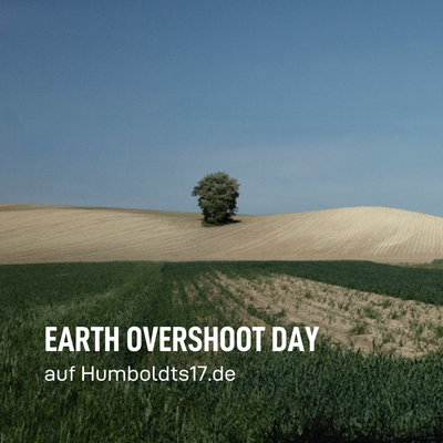 Earth Overshoot Day. Im Hintergrund ist ein hügeliges abgeerntetes staubig aussehendes Feld abgebildet. Im Vordergrund ist noch nicht abgeerntetes Feld mit grünen Getreideähren.