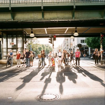 Menschen stehen im Sommer an einer Ampel.