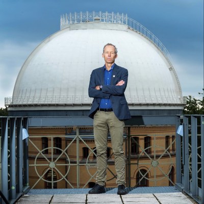 Prof. Dr. Johan Rockström is standing on a balcony with a tower of the old Astrophysical Observatory Potsdam building in the background.