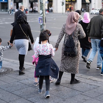 Frauen, die mit Kindern an der Hand über die Straße gehen