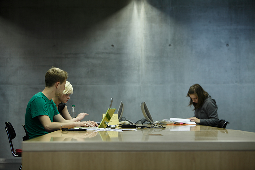 Studierende in einem Arbeitsraum vor Notebooks
