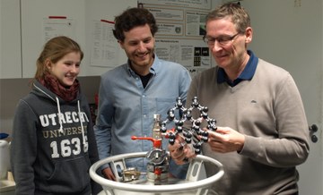 PB011167 bearbeitet Merle Braun, Bernd Sontheimer, Oliver Benson lehnen sich an einen Stickstoff-Tank in einem der LASER-Labore des Instituts für Nanooptik. In den Händen von Herrn Benson ein Atommodell eines Diamanten mit Einschlüssen.