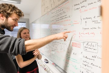 SUE13062 016 Studierende stehen an einer Tafel