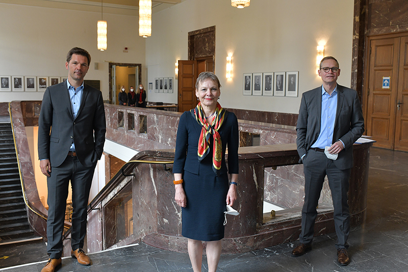 PLA 4027 01 Steffen Krach, Sabine Kunst and Michael Müller stand in front of stairs in the main building of Humboldt-Universität
