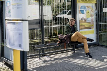 Student wartend an einer Bushaltestelle