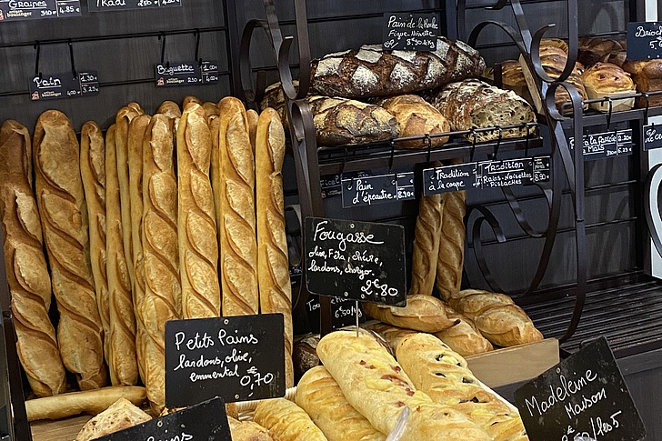 Regal mit verschiedenen Baguettes, Broten und Gebäck in einer Bäckerei mit handbeschrifteten Preisschildern