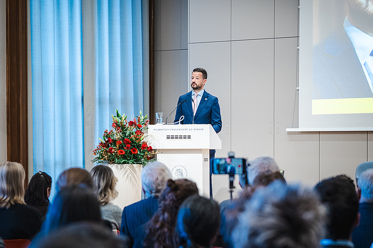 Jacov Milatović wie er am Pult steht und seine Rede hält. Im vorderen Teil des Bildes befindet sich Publikum, das mit dem Rücken zur Kamera sitzt.