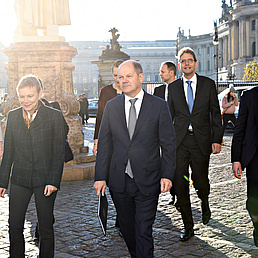 Olaf Scholz, Prof. Matthias Ruffert, Sabine Kunst und andere laufen über den Vorhof des Hauptgebädes.
