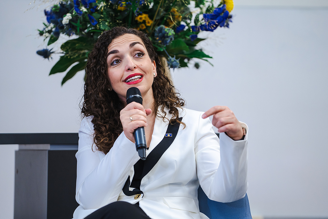 Vjosa Osmani-Sadriu wie sie auf einem Stuhl sitzend eine Frage aus dem Publikum beantwortet.