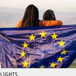 Zwei Frauen halten die Europäische Flagge und halten sich im Arm.