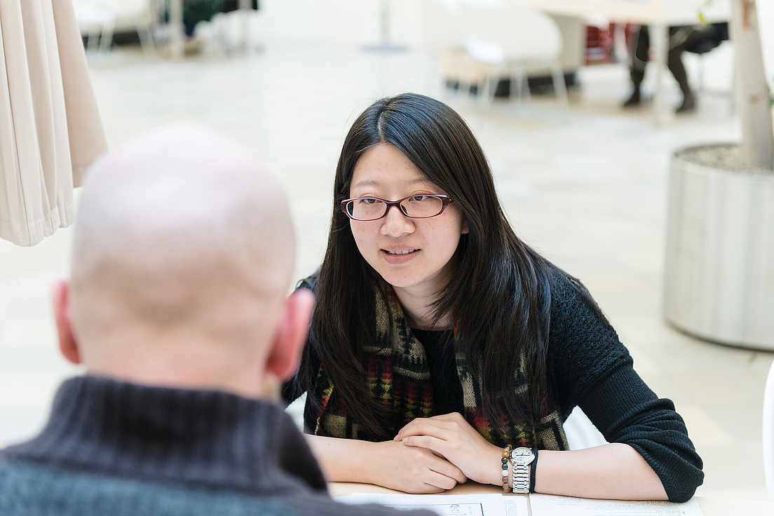 Two people sit at a table in a counselling session
