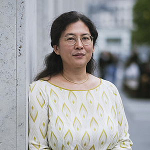 Yong-Mi Rauch, Leiterin der Abteilung Historische Sammlungen der HU-Universitätsbibliothek Yong-Mi Rauch lehnt an einer Hauswand in einer Berliner Straße.