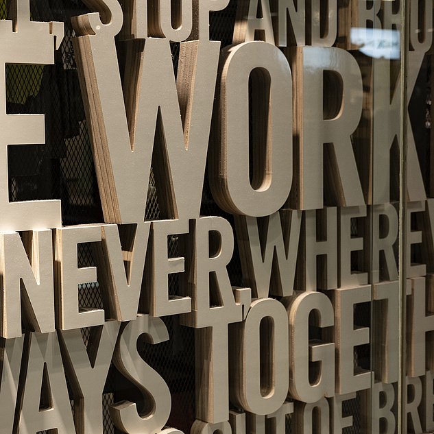 In großen Lettern steht hinter einer Glasscheibe "We Work When We Work Always Together"