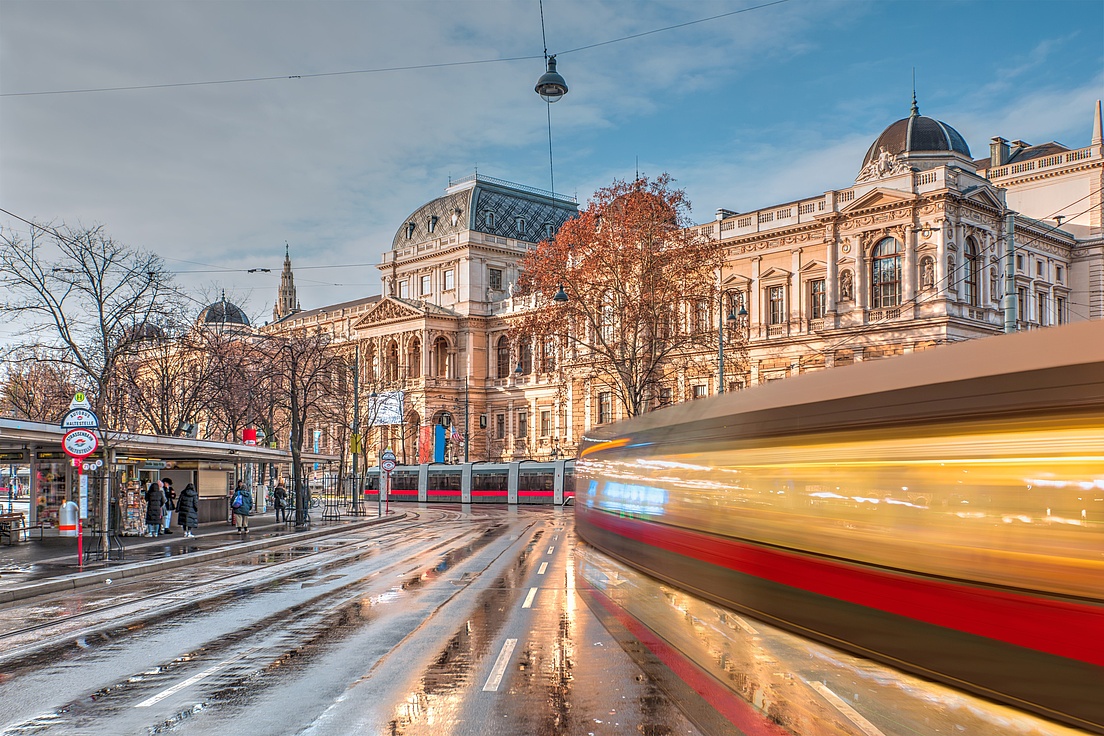 Tram moving on a street in the foreground - View of the University of Vienna (Universitat Wien) - Vienna, Austria Tram moving on a street in the foreground - View of the University of Vienna