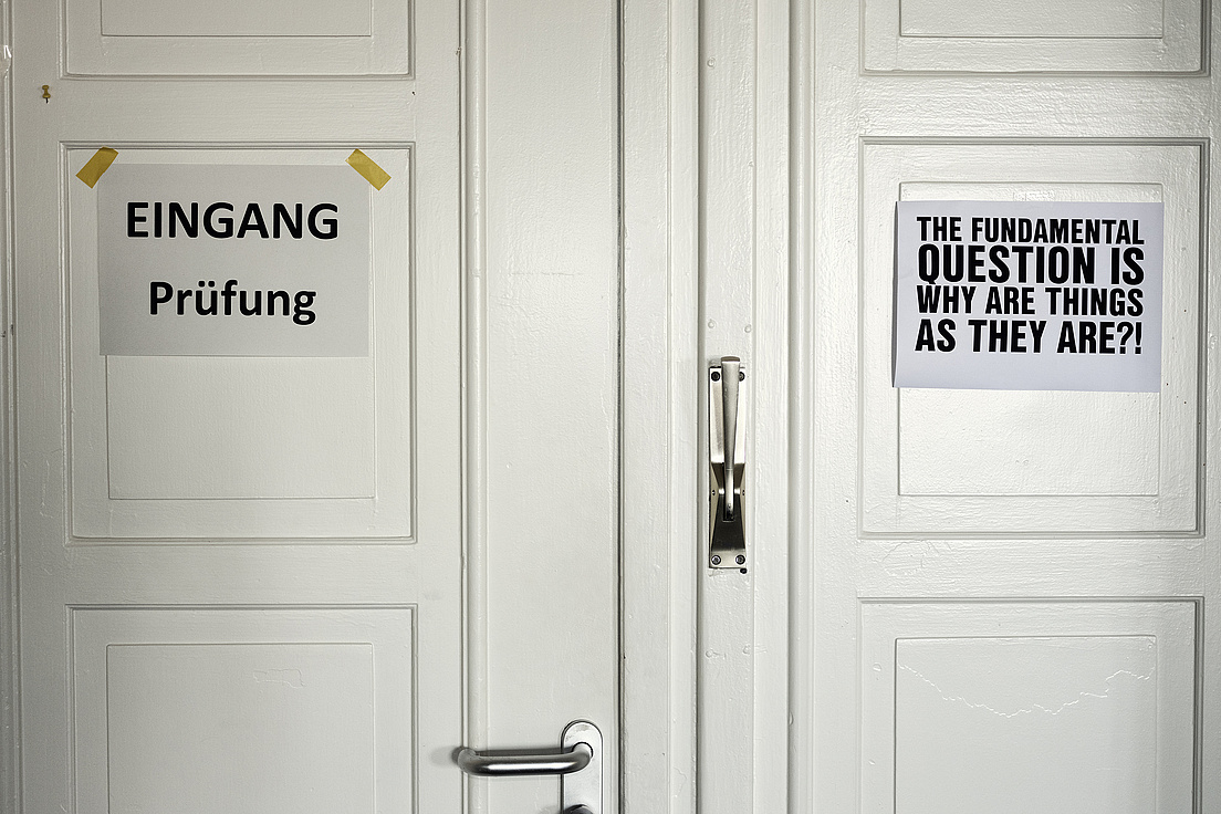 Eingang zur Prüfung Eine Tür mit einem Schild "Eingang Prüfung" und einem Schild auf dem steht "the fundamental question is why are things as they are?!" in Großbuchstaben.