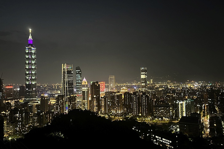 Nächtliche Stadtansicht mit beleuchteten Hochhäusern und dem markanten Taipei 101 links im Bild