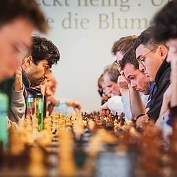 Eine lange Tischreihe mit zahlreichen Schabrettern, an denen Partien ausgetragen werden.