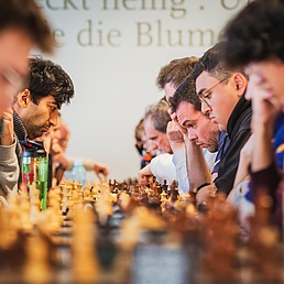Eine lange Tischreihe mit zahlreichen Schabrettern, an denen Partien ausgetragen werden.
