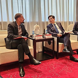 3 gesessene Männer reden zusammen.