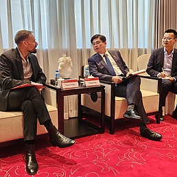 Three seated men are talking together.
