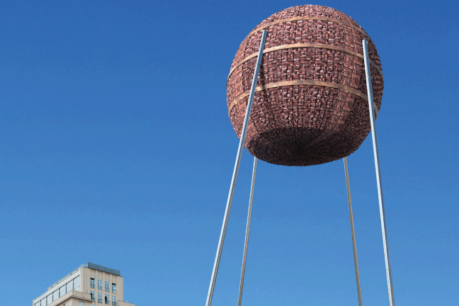 Ein Objekt aus Rinde, überlebensgroß, steht auf Stelzen am Strausberger Platz in Berlin 