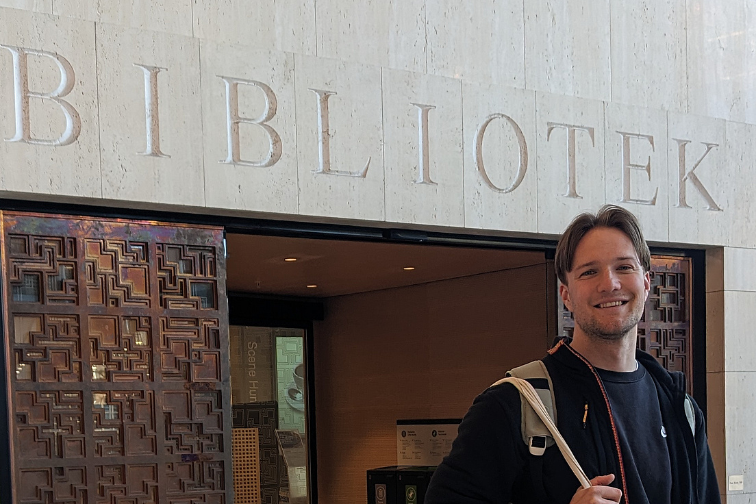 Fassade eines Gebäudes mit der Aufschrift 'BIBLIOTEK' über einem Eingang und einer Person mit Rucksack davor
