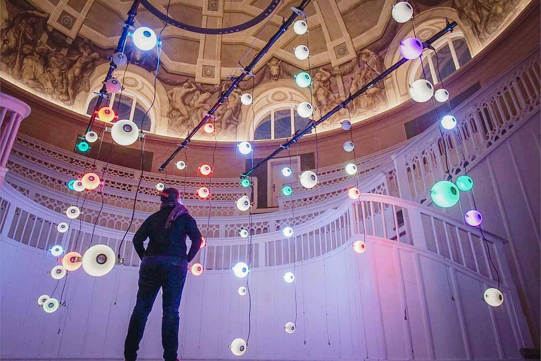 Theatre of Memory im Tieranatomischen Theater Ein Mensch steht im Hörsaal des Tieranatomischen Theaters der HU und beatrachtet eine farbige Licht-Installation.