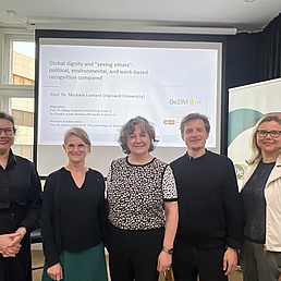 Group of 5 people in a photograph in front of a slide show on a sociological topic.