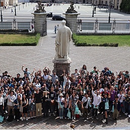 A group of people gather in the main square of the HU's main building.