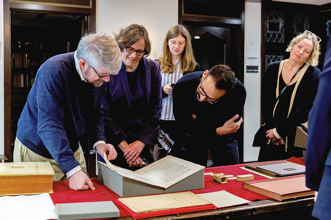 People view an old book in a library.