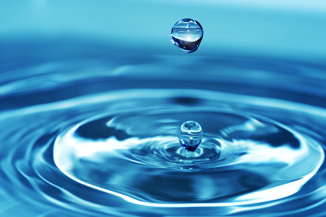 Splash water Nahaufnahme eines Wassertropfens, der auf eine Wasseroberfläche mit kreisförmigen Wellen fällt