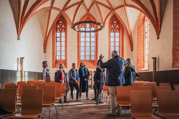 Führung in der Heilig-Geist-Kapelle Im Innern der Heilig-Geist-Kapelle der HU. Eine Gruppe von Menschen hören einem Mann zu der mit Händen gestikuliert.