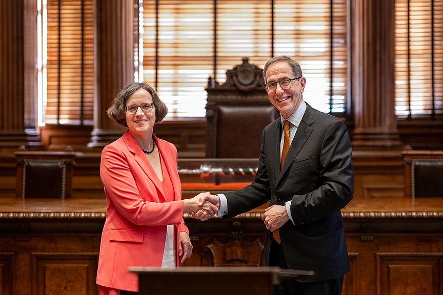 Ein Mann und eine Frau, die sich freundschaftlich die Hände schütteln und dabei lachen.