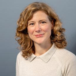 Anette Eva Fasang hat einen beigen Pullover an und blickt freundlich in die Kamera. Der Hintergrund hat eine graue Farbe.