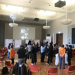 Teilnehmer*innen der Autumn School 2025 Teilnehmer*innen im Rahmen der Autumn School stehen in kleinen Gruppen im Senatssaal der HU. Im Hintergrund stehen Pinwände.