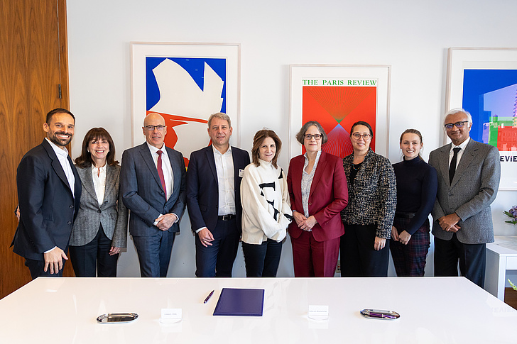 Gruppenfoto der Vertreter der HU und der NYU hinter einem weißen Tisch und vor einer weißen Wand mit Gemälden