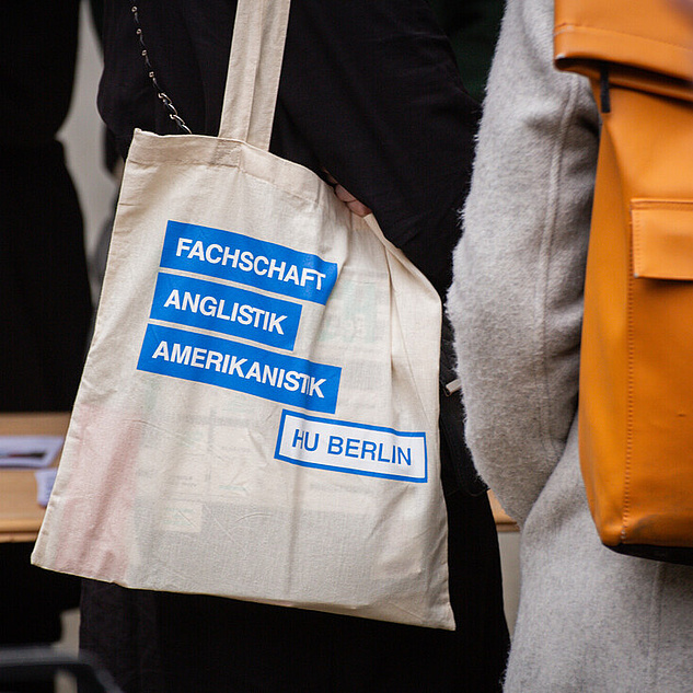 Immatrikulationsfeier Eine Stofftasche hängt über der Schulter einer Person. Auf der Stofftasche steht "Fachschaft Amerikanistik, Anglistik. HU Berlin."