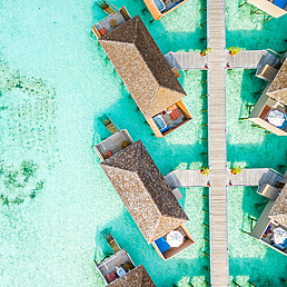 Stelzenhäuser im türkisen Wasser der Malediven, von oben fotografiert