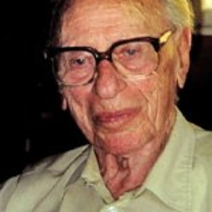 A photo of Siegfried Adlerstein, looking to the bottom left of the camera, wearing glasses and smiling slightly