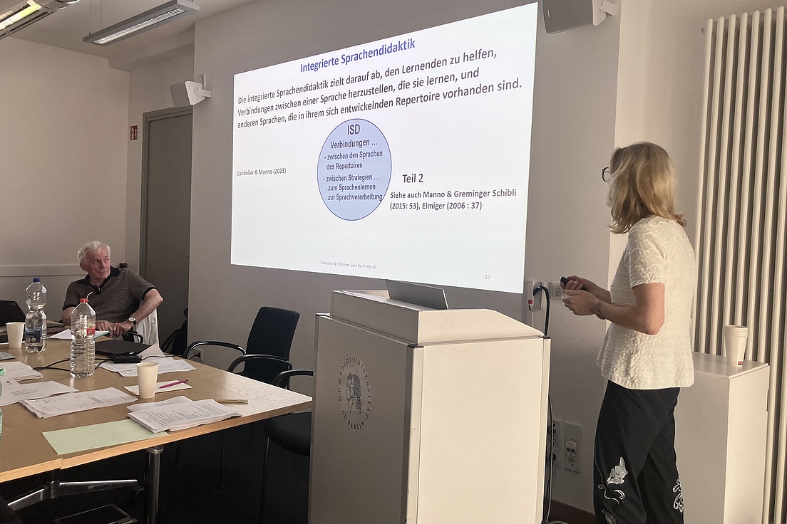 A teacher looks at a blackboard onto which a slideshow from a lecture is projected.