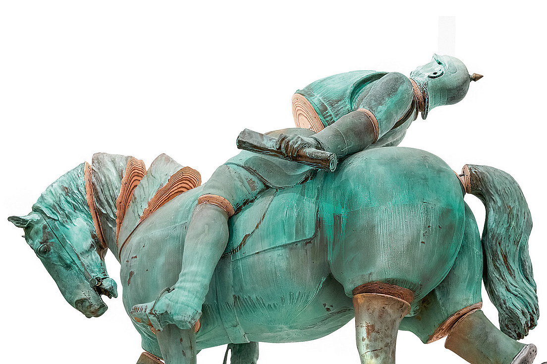 Verkleinerte Version des Bremer Reiterstandbilds von Otto von Bismarck aus Holz, das in einzelne Glieder zerlegt wurde. Das Pferd hat den Kopf gesenkt und Otto v. Bismarck liegt mit dem Rücken auf dem Pferderücken mit Blick nach oben.