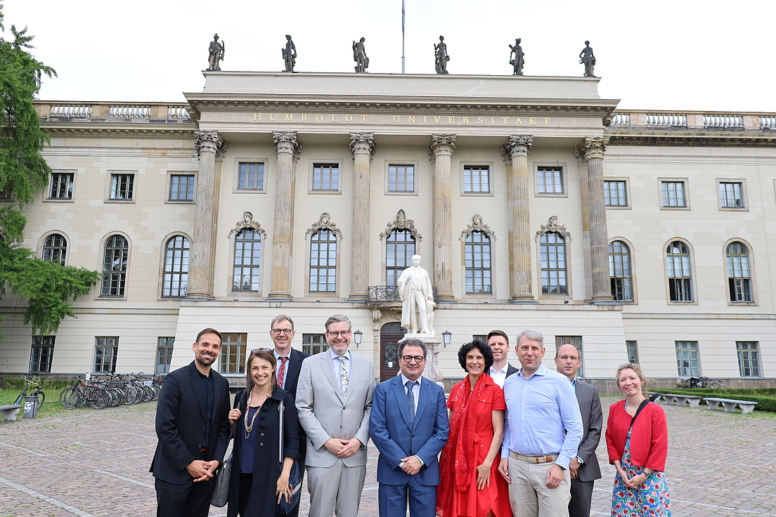A group of women and men pose for a photo in front of the façade of the HU's main building.