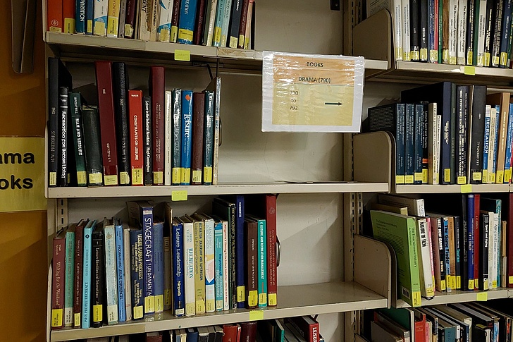 Regalabschnitt mit Büchern, links ein Schild mit der Aufschrift 'Drama Books'