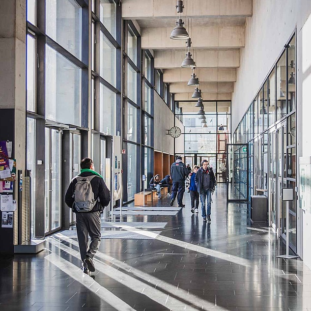 Erwin-Schrödinger-Zentrum Studierende laufen durch die hohe lichtdurchflutete Foyerhalle des Erwin-Schrödinger-Zentrums der HU.